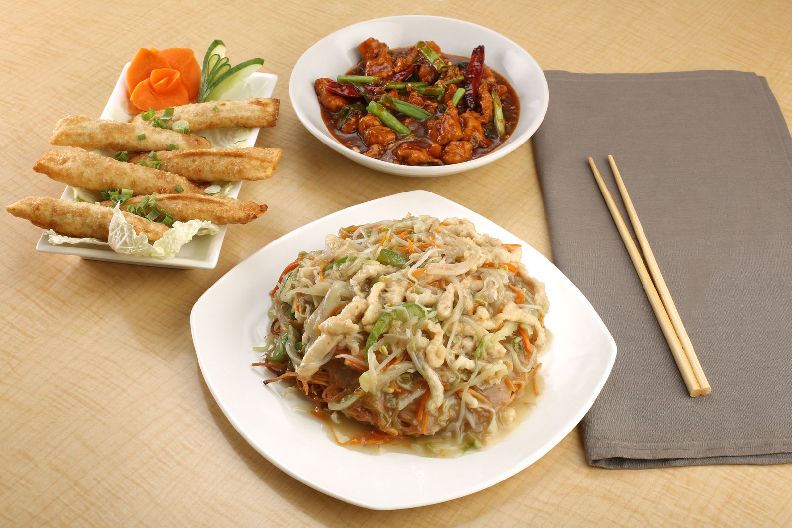 Asian meal with noodles, stir-fry and spring rolls on a table