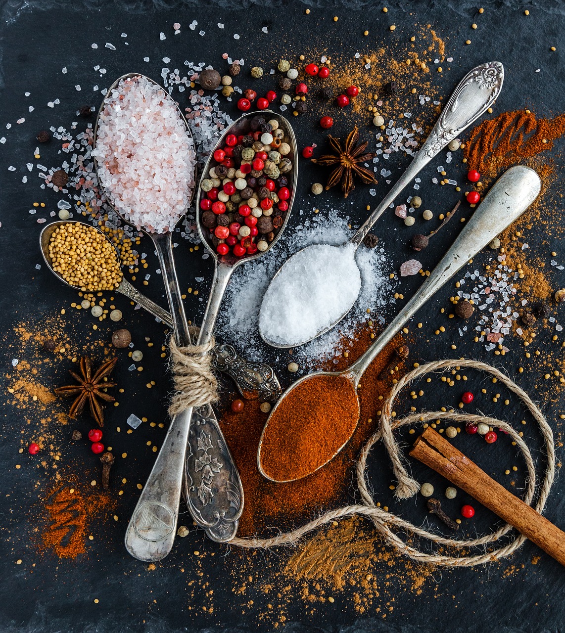 Assorted whole spices and ground powders on a dark surface