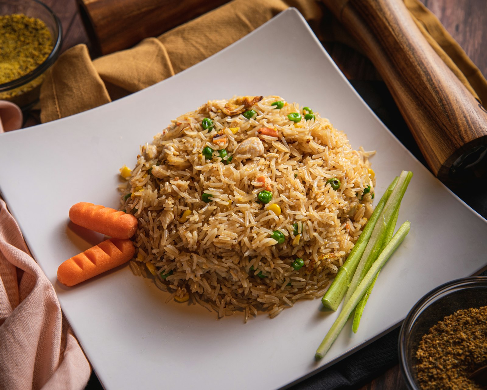 Fried rice with peas and carrots on a white square plate