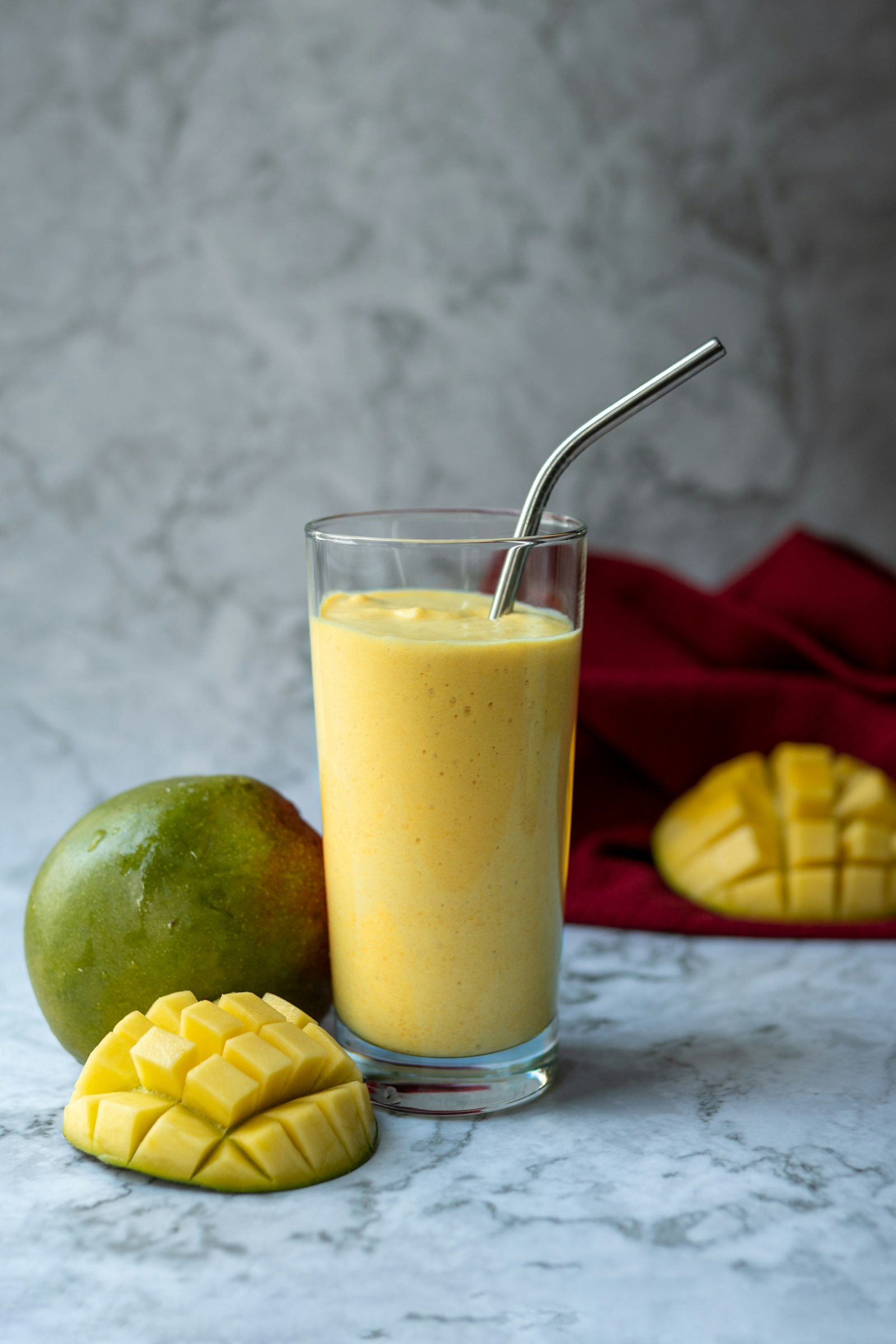 Glass of mango lassi beside a fresh mango