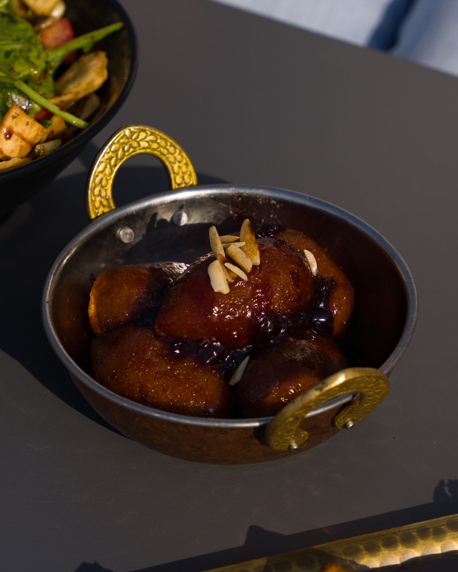 Gulab jamun dessert in a decorative brass bowl